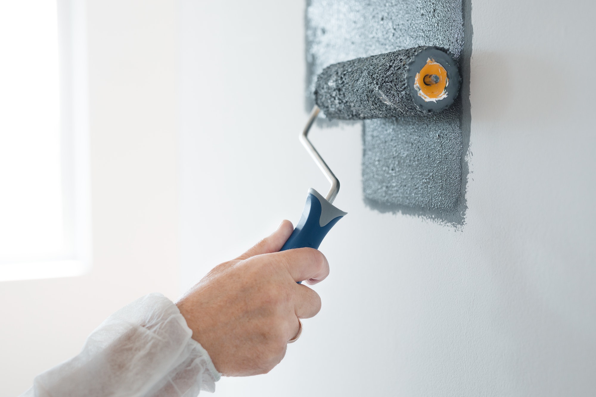 Closeup of renovation crew painting wall grey with painting roll
